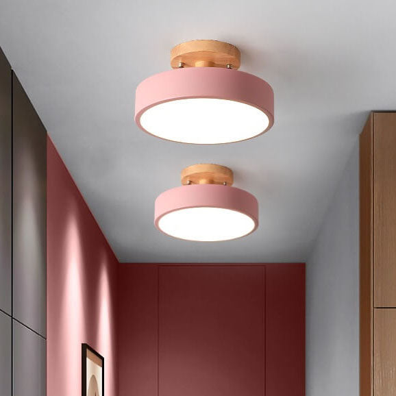 Two pink ceiling lights with wooden accents in a room with red walls and wooden furniture.