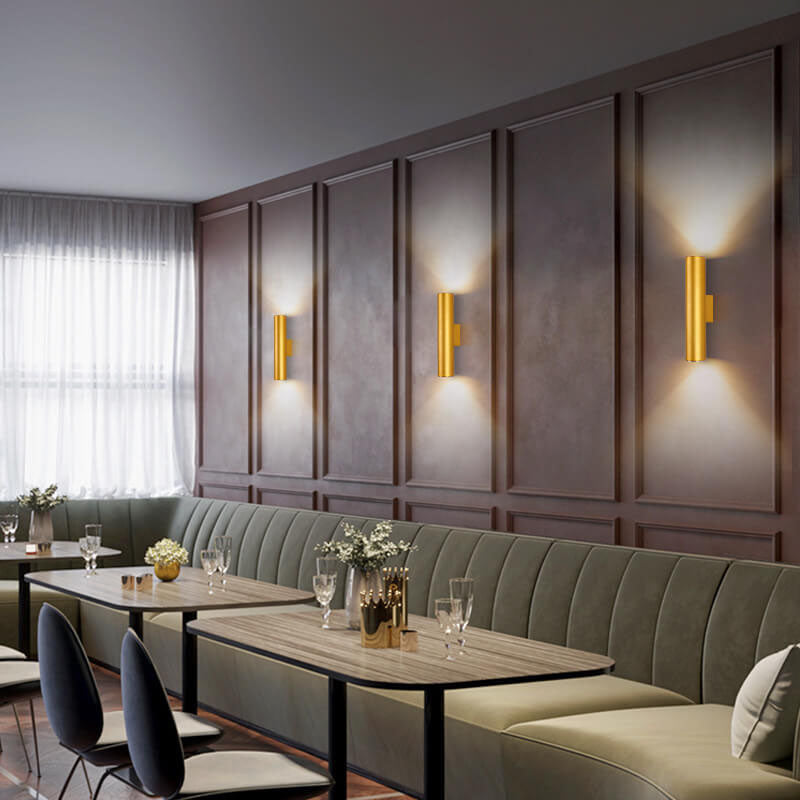 Modern restaurant interior with gray upholstered booths, wooden tables, and wall-mounted lights.