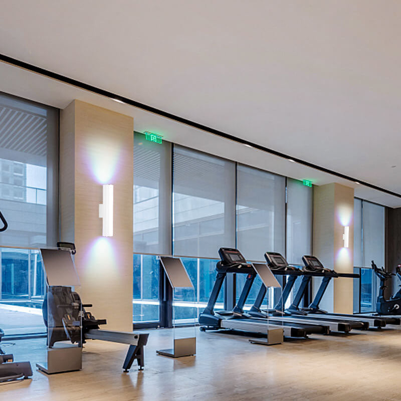 Modern gym interior with treadmills and exercise bikes near large windows.
