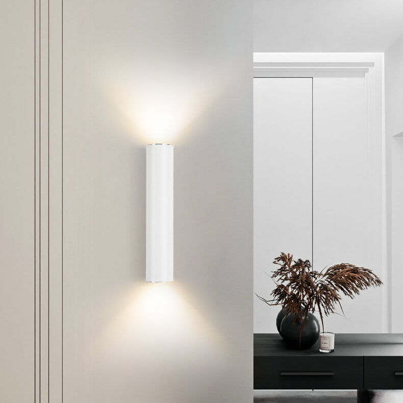 Modern wall-mounted light fixture on a neutral wall with a mirror and decorative elements.