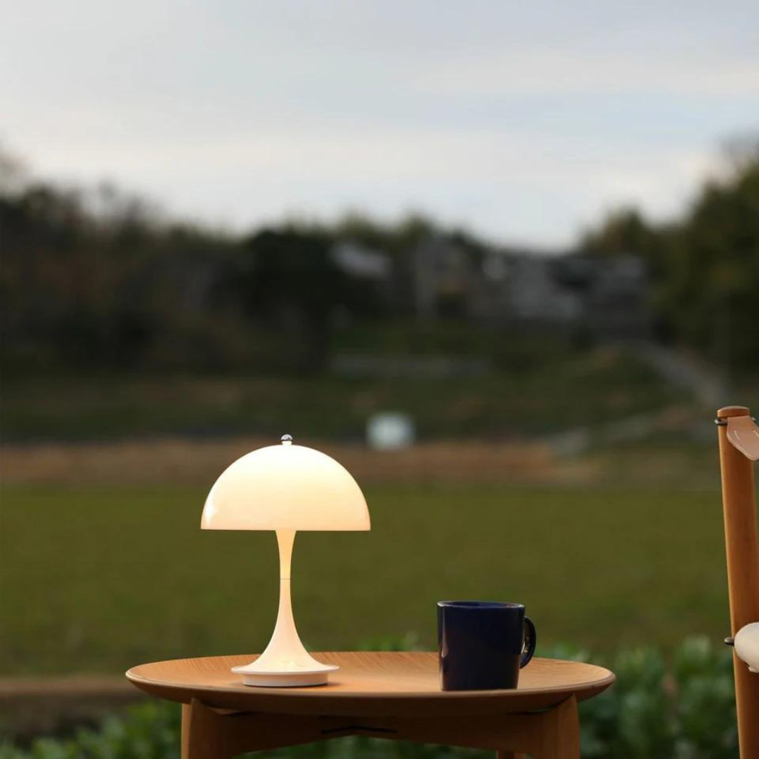 Table lamp and mug on a wooden table with a blurred natural background