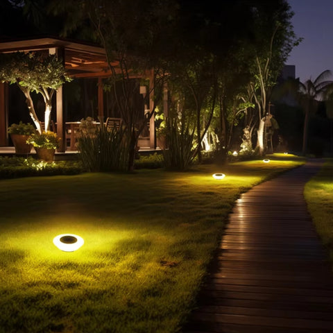 Garden pathway with solar lights illuminating a wooden deck and outdoor furniture.