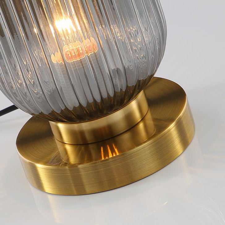 Table lamp with ribbed glass shade and gold base on a white background
