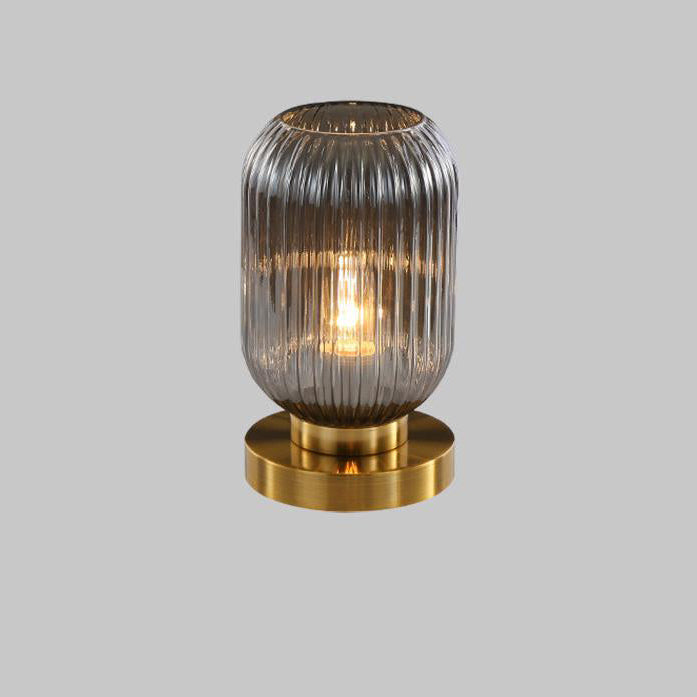 Table lamp with ribbed glass shade and gold base on a gray background