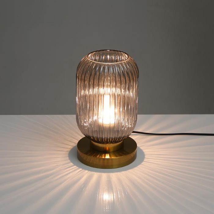 Table lamp with ribbed glass shade and brass base on a neutral background