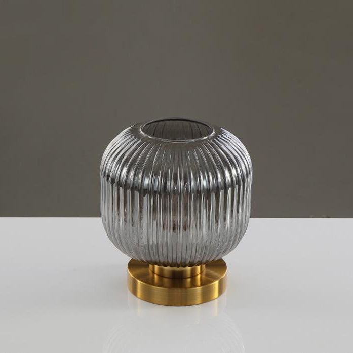 Decorative lamp with ribbed glass shade and gold base on a gray background