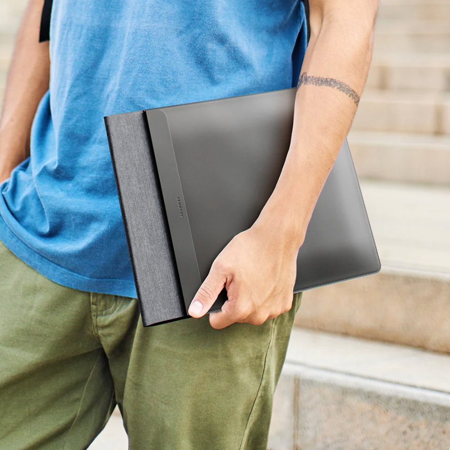 Person holding a black laptop case with a blurred background