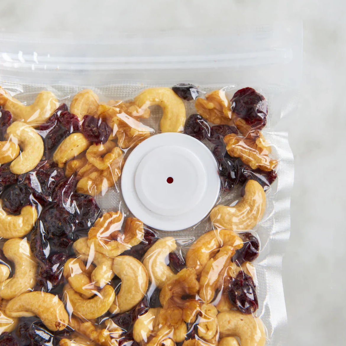 Vacuum-sealed package of cashews and cranberries on a white background