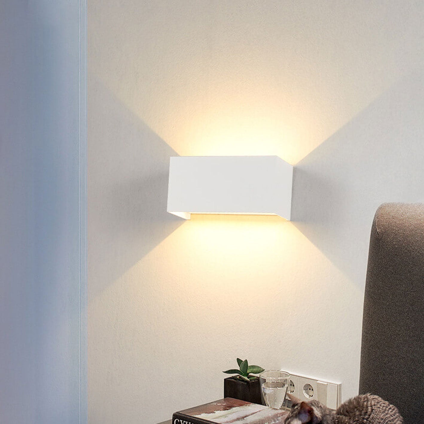 Modern wall-mounted light fixture on a white wall with a soft glow.