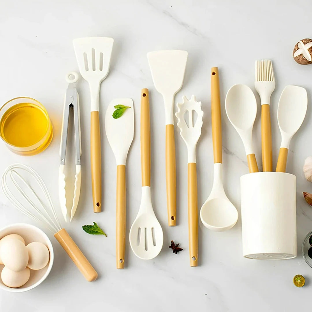Set of kitchen utensils with wooden handles on a light surface.