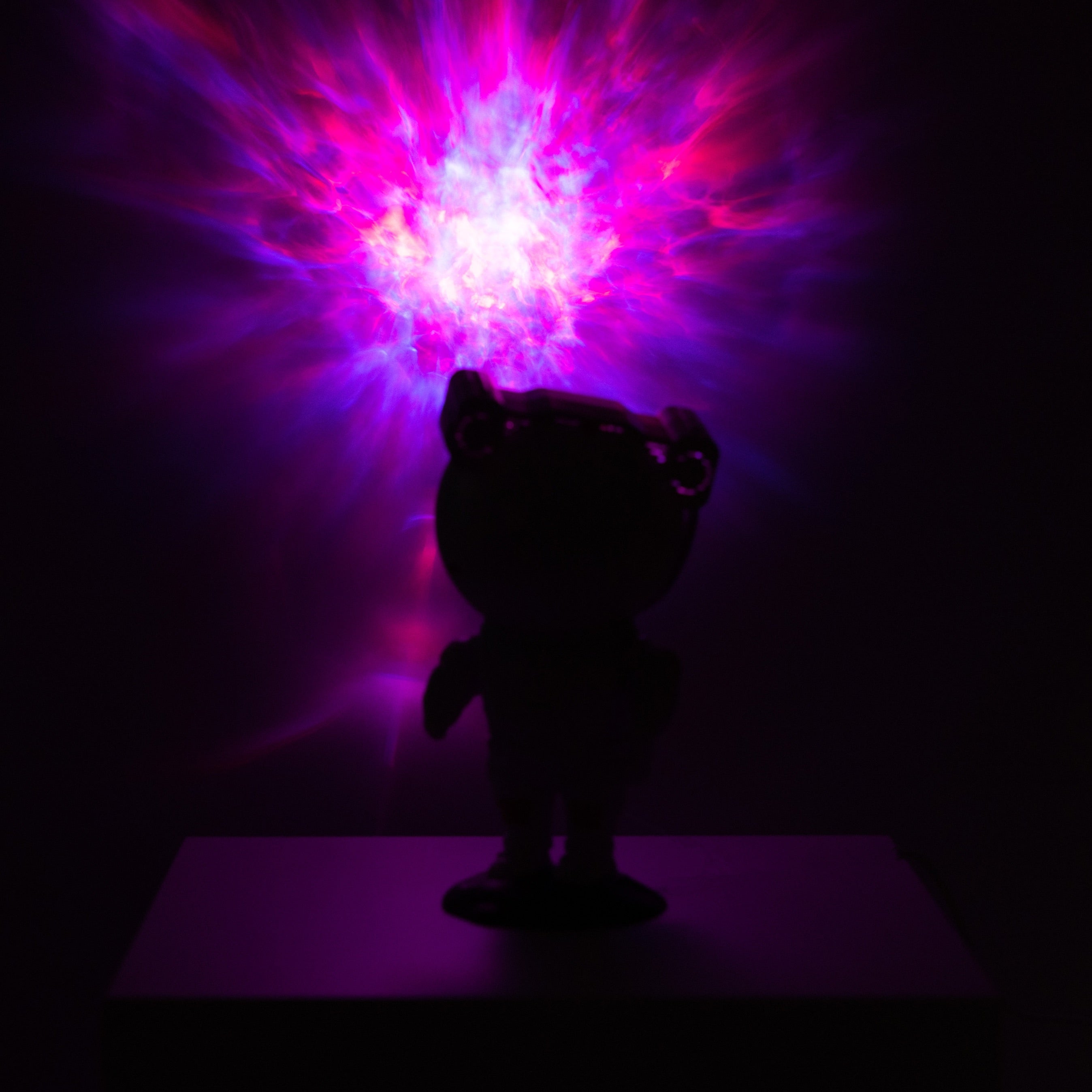 Silhouette of a bear figurine with a vibrant, colorful light display in the background