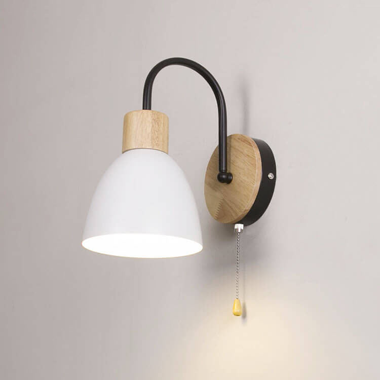 Wall-mounted lamp with white shade, wooden base, and black arm on a gray wall.
