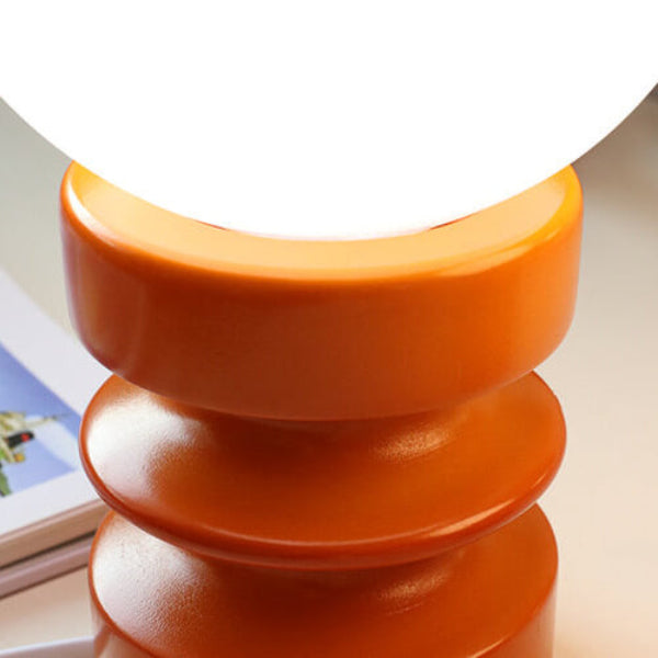 Orange cylindrical object on a reflective surface with a blurred background