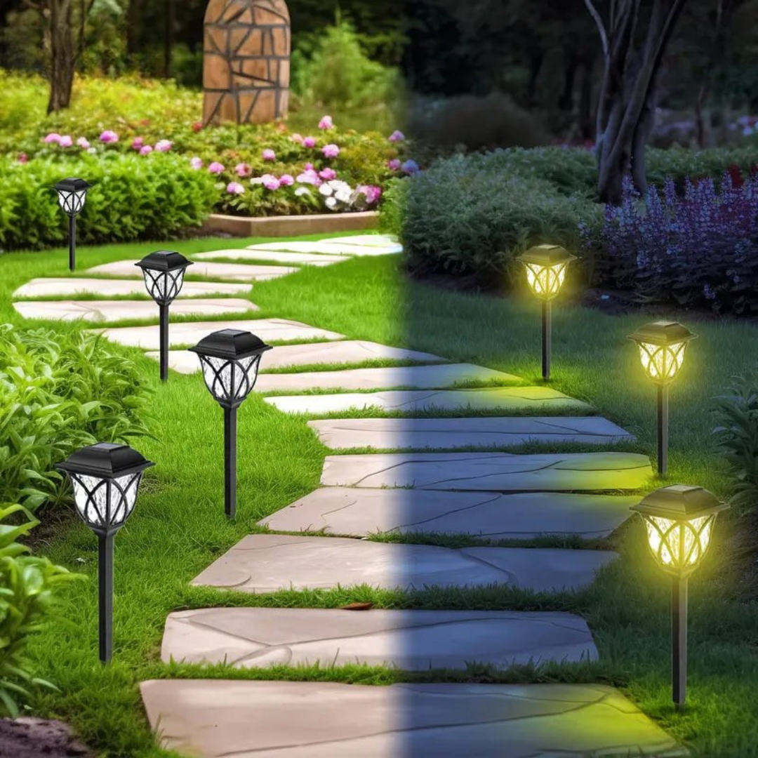 Solar garden lights illuminating a stone pathway in a garden with flowers and plants.