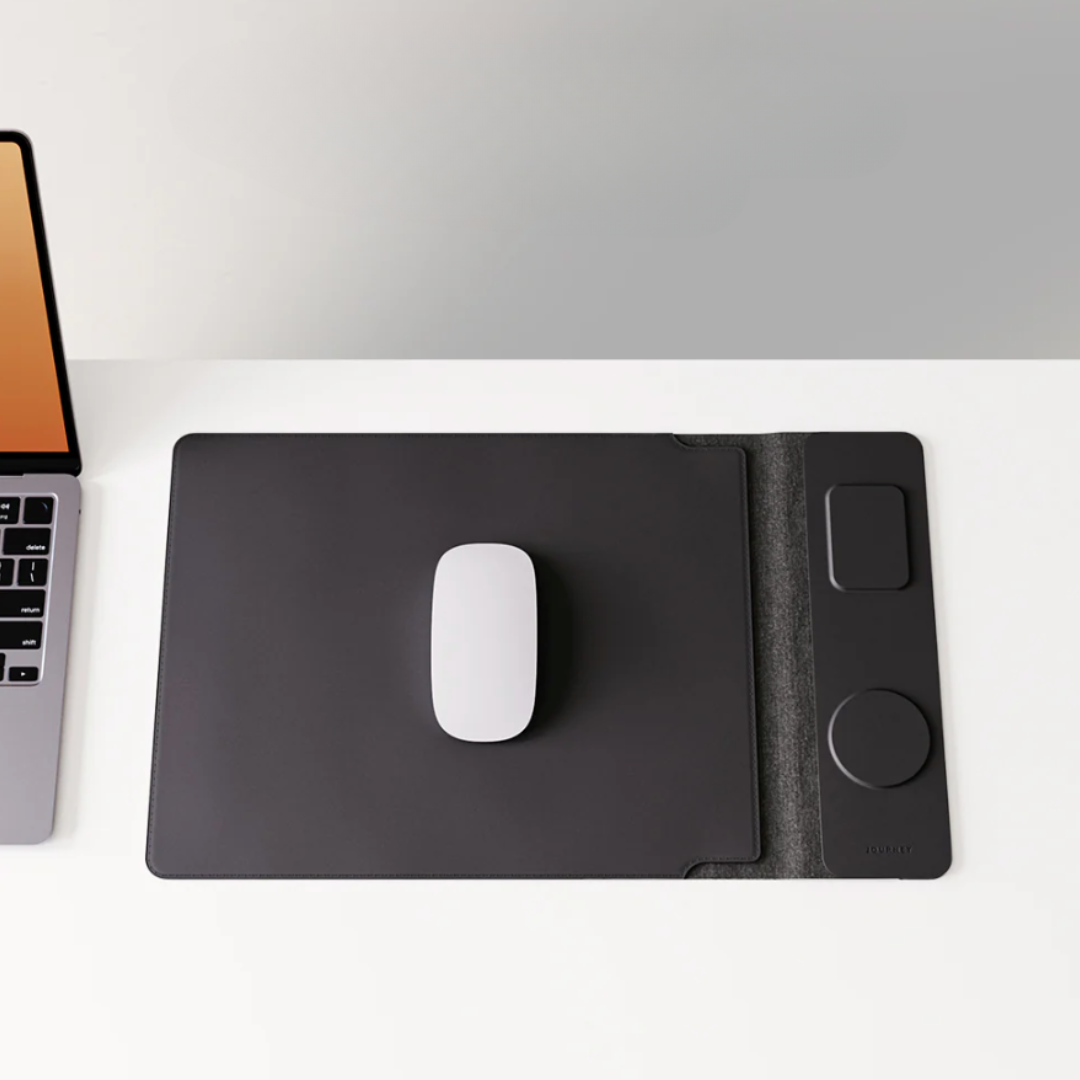 Black graphic tablet with a white mouse on a white surface next to a laptop.