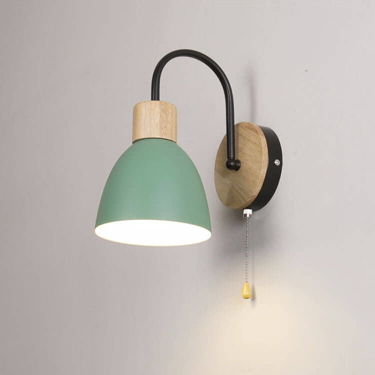 Wall-mounted lamp with green shade and wooden base on a plain wall
