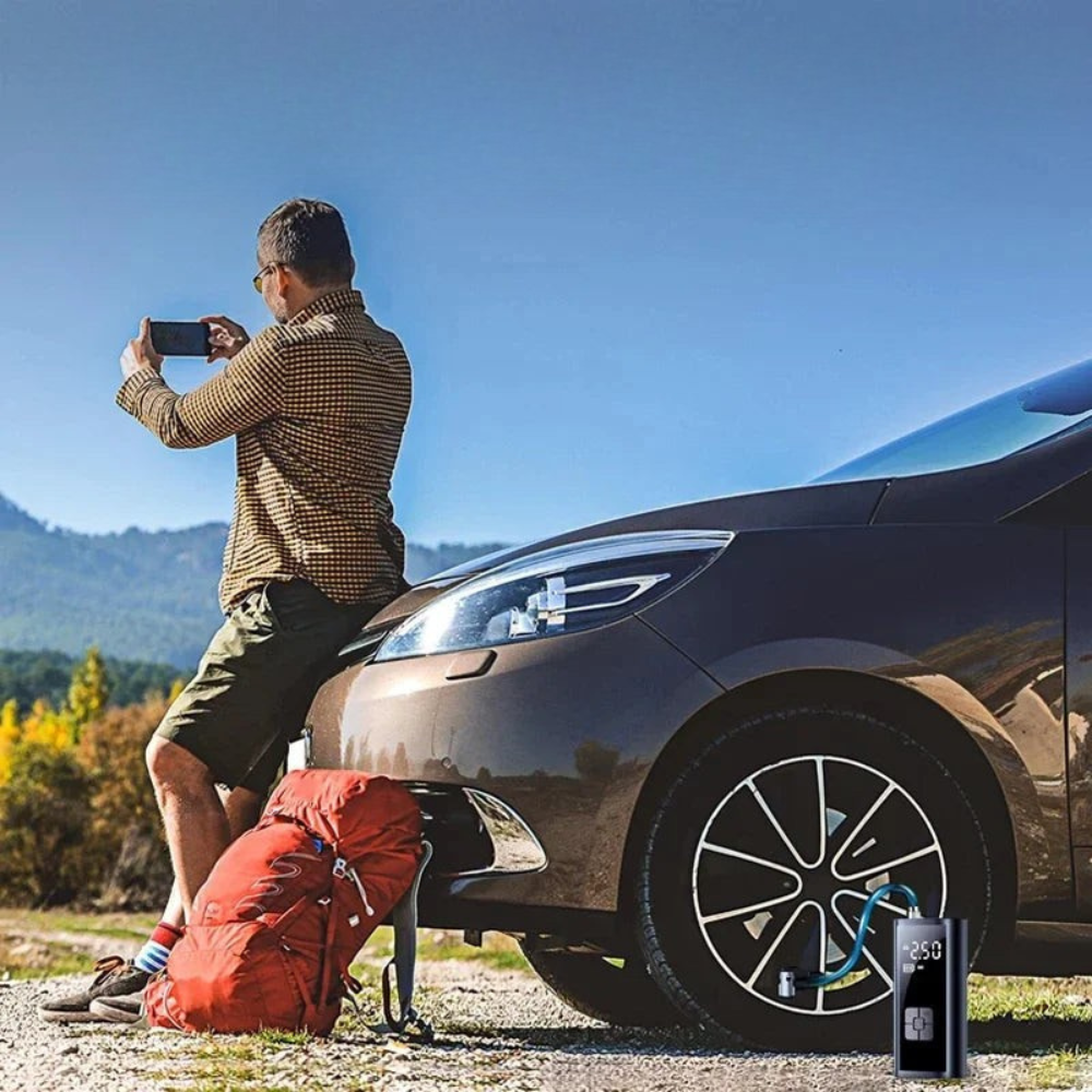Man taking a photo of a car with a phone, mountains in the background