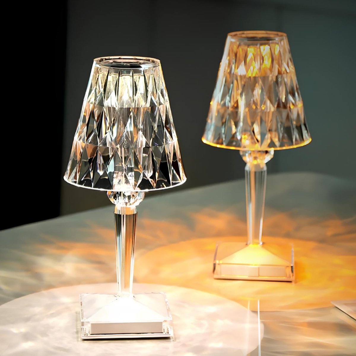 Two decorative table lamps with crystal-like shades on a reflective surface.