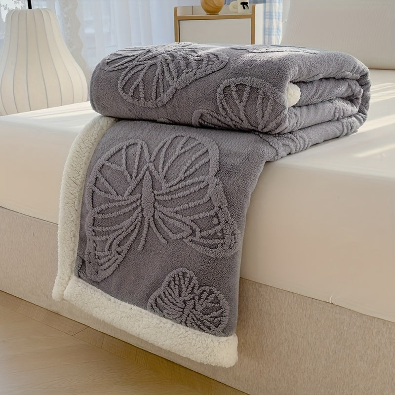 Gray butterfly-patterned blanket on a bed with a white background