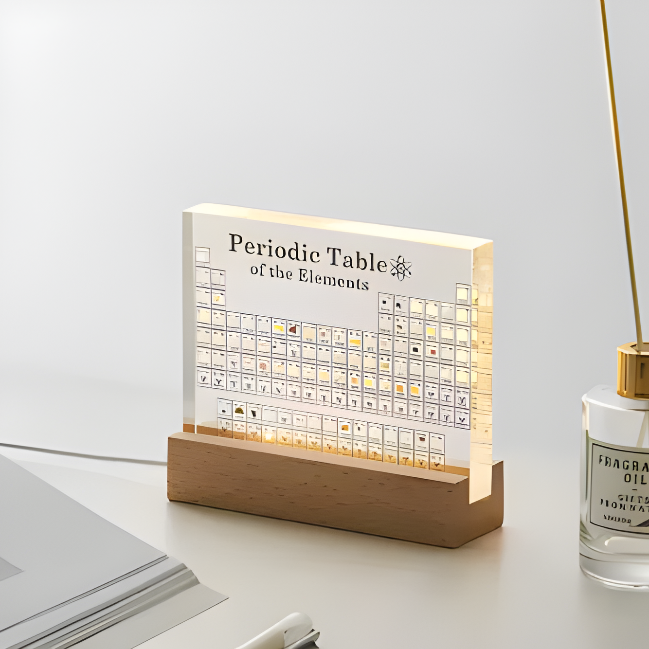 Luminescent periodic table of elements on a wooden stand with a clear bottle of perfume in the background.