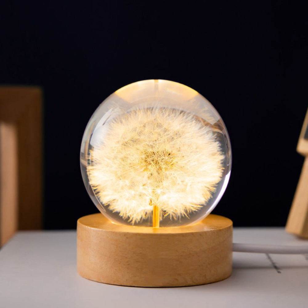 Decorative lamp with a dandelion inside a glass sphere on a wooden base.