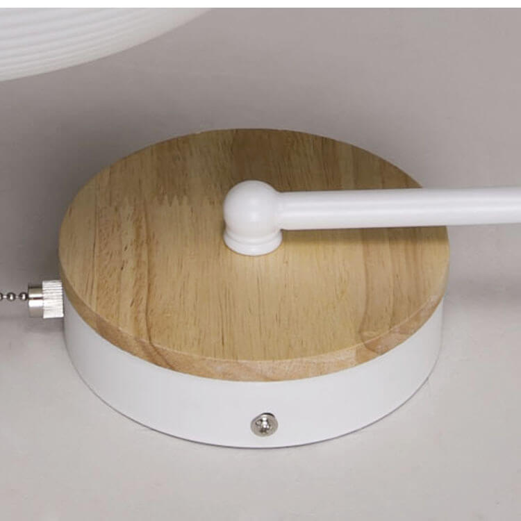 Close-up of a wooden lamp base with a white pull cord switch on a neutral background