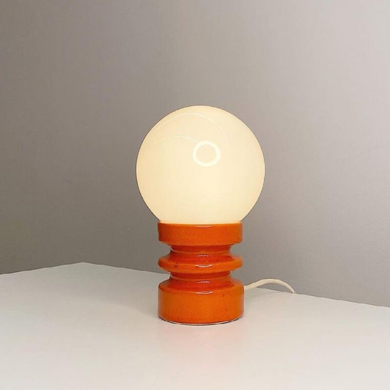 Table lamp with a wooden base and white glass shade on a neutral background