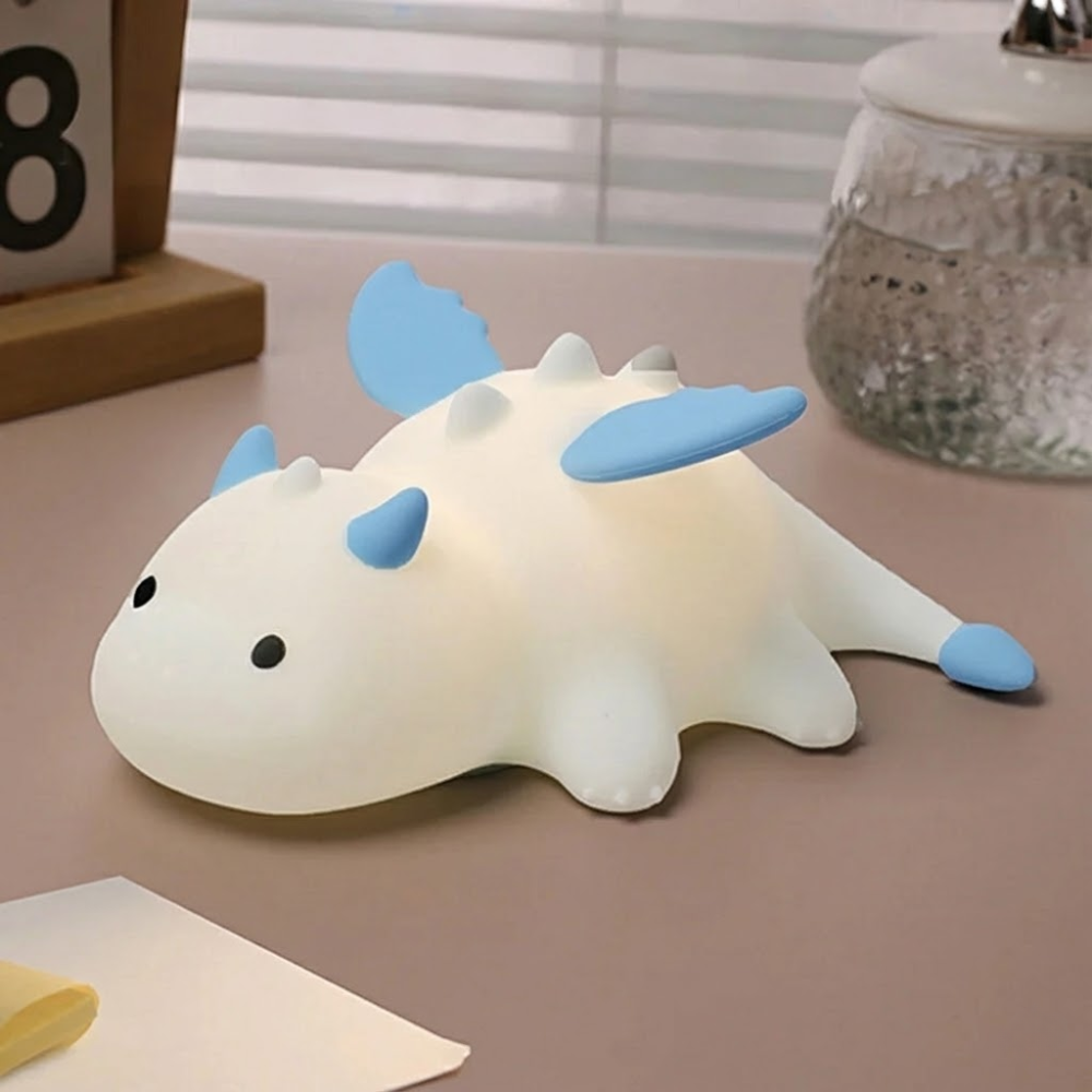 White dragon-shaped night light with blue accents on a desk