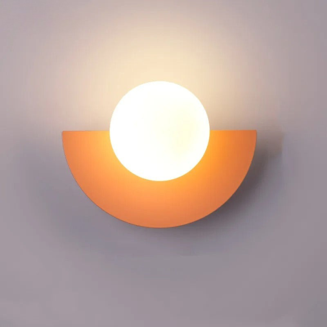 Wall-mounted light fixture with a half-circle orange base and white bulb on a gray background