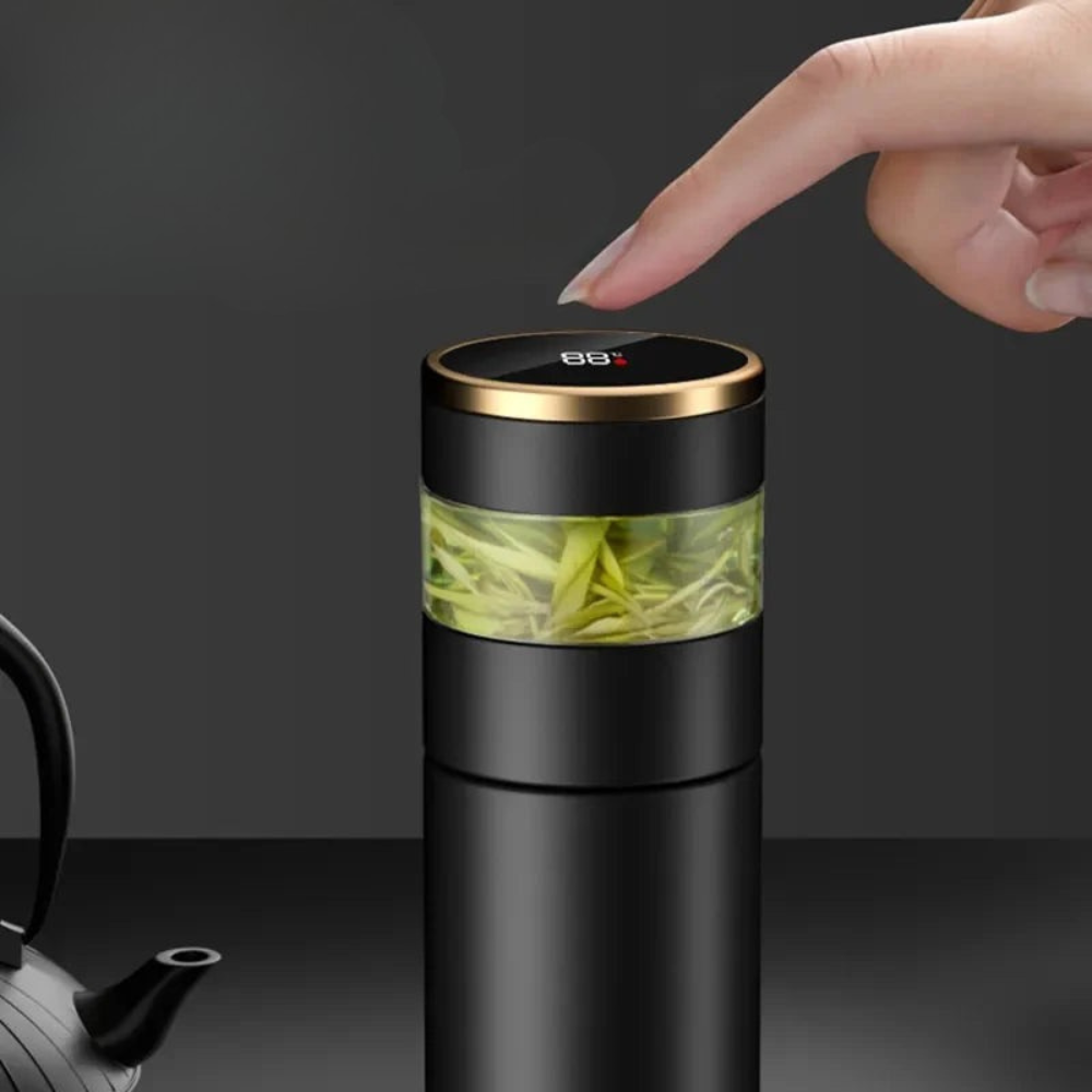 Black tea infuser with green tea leaves and a hand pressing a button on a dark background