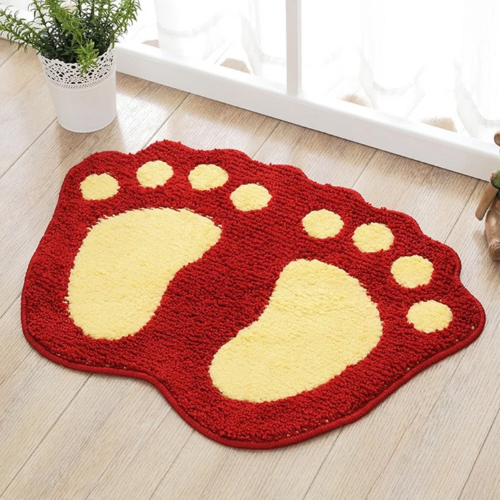 Red and yellow foot-shaped rug on a wooden floor with a plant in the background.