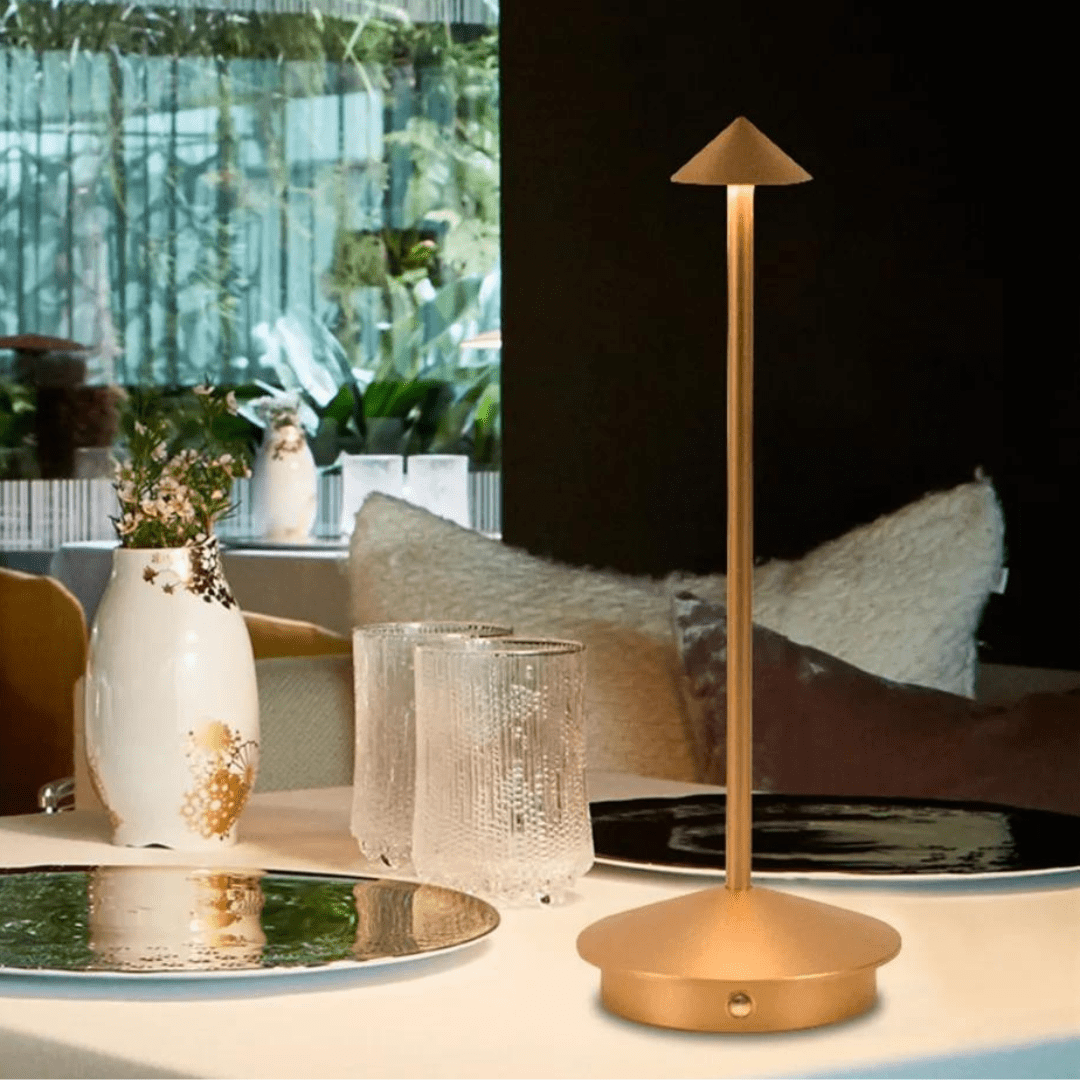 Gold table lamp on a table with decorative items in a room setting
