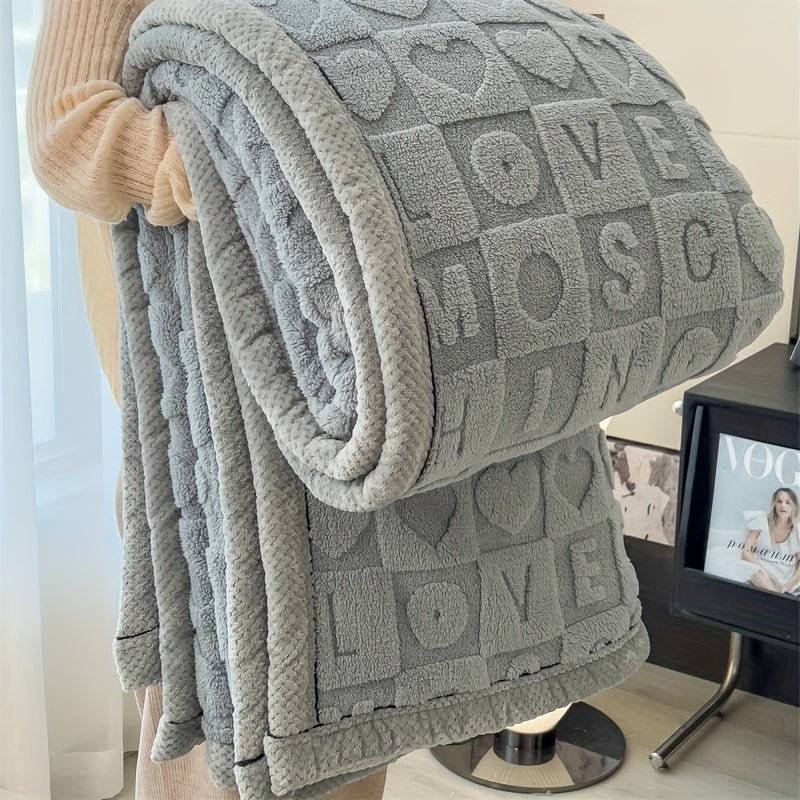 Gray textured blanket with 'LOVE' pattern draped over a chair in a room.
