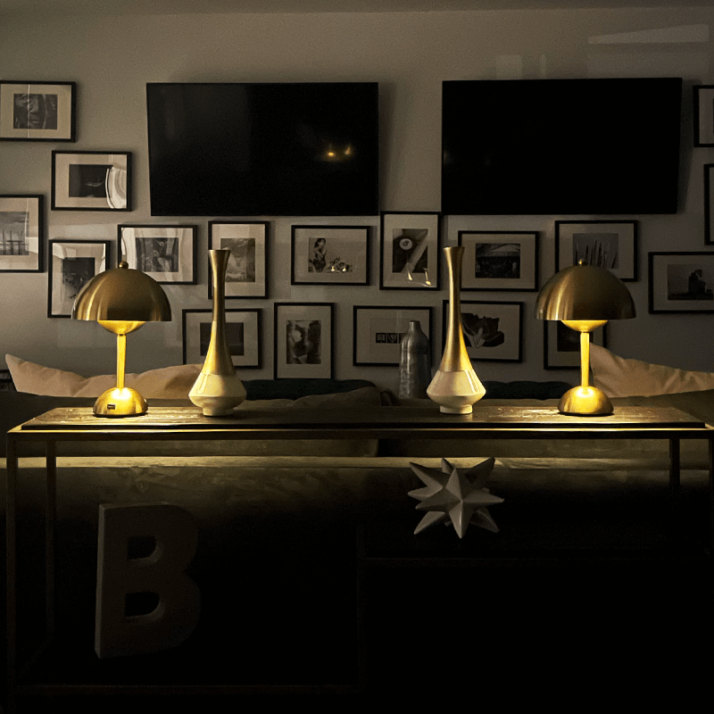 Modern living room with gold lamps, decorative vases, and framed pictures on a wall.