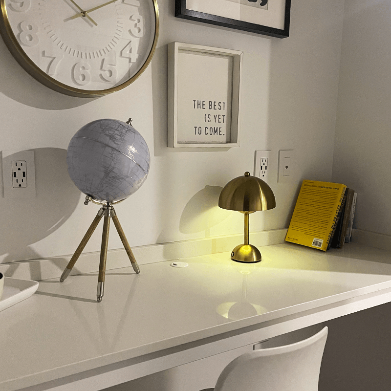 Decorative items on a white surface including a clock, globe, lamp, and framed quote.