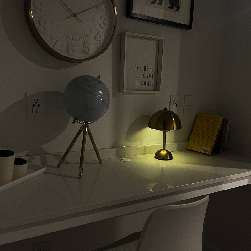 Dark room with desk, globe, lamp, and motivational quote on wall