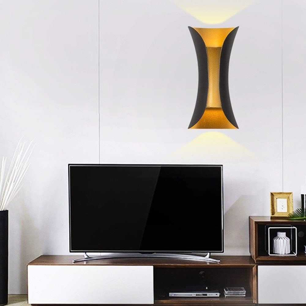 Modern living room with a television on a wooden stand, decorative wall light, and small table with decor items.