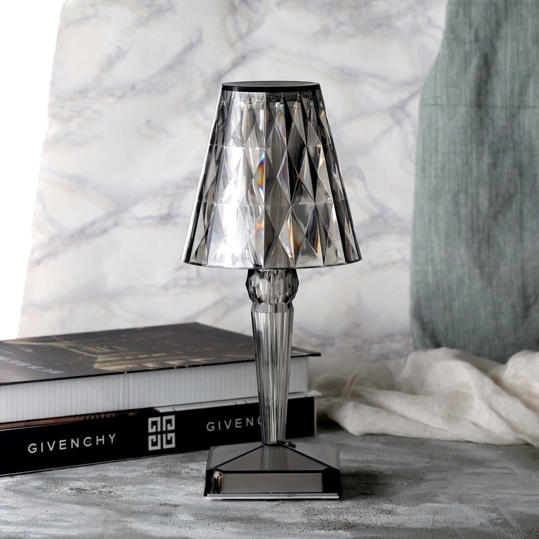 Crystal table lamp on a surface with books and a textured wall in the background