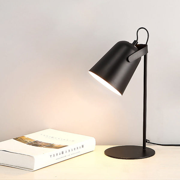 Black desk lamp on a surface with a book next to it