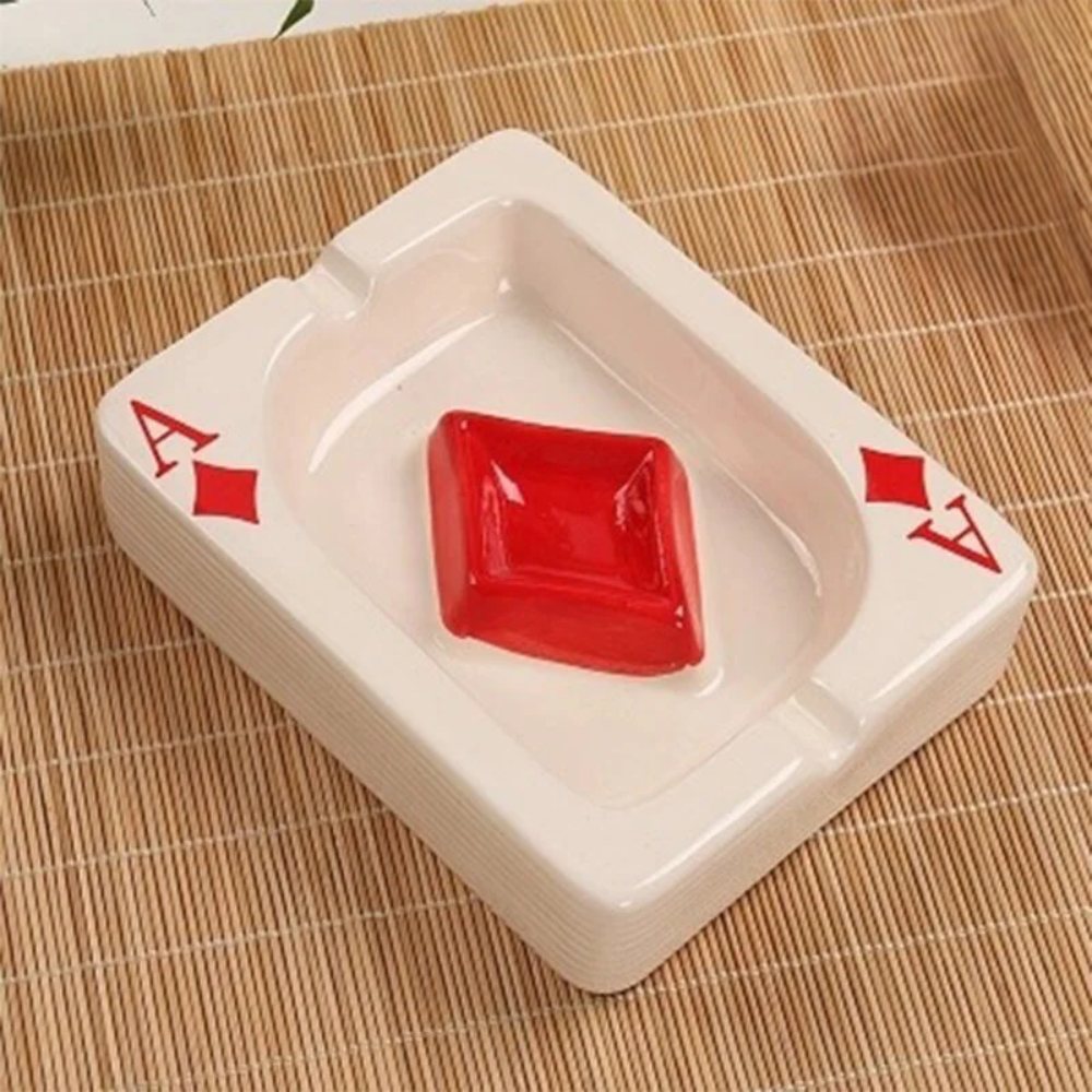 White ashtray with red gemstone and 'A' symbol on a woven mat