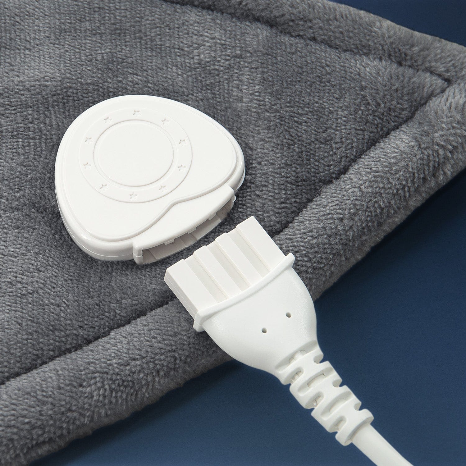 Gray heating pad with white control unit and plug on a blue background