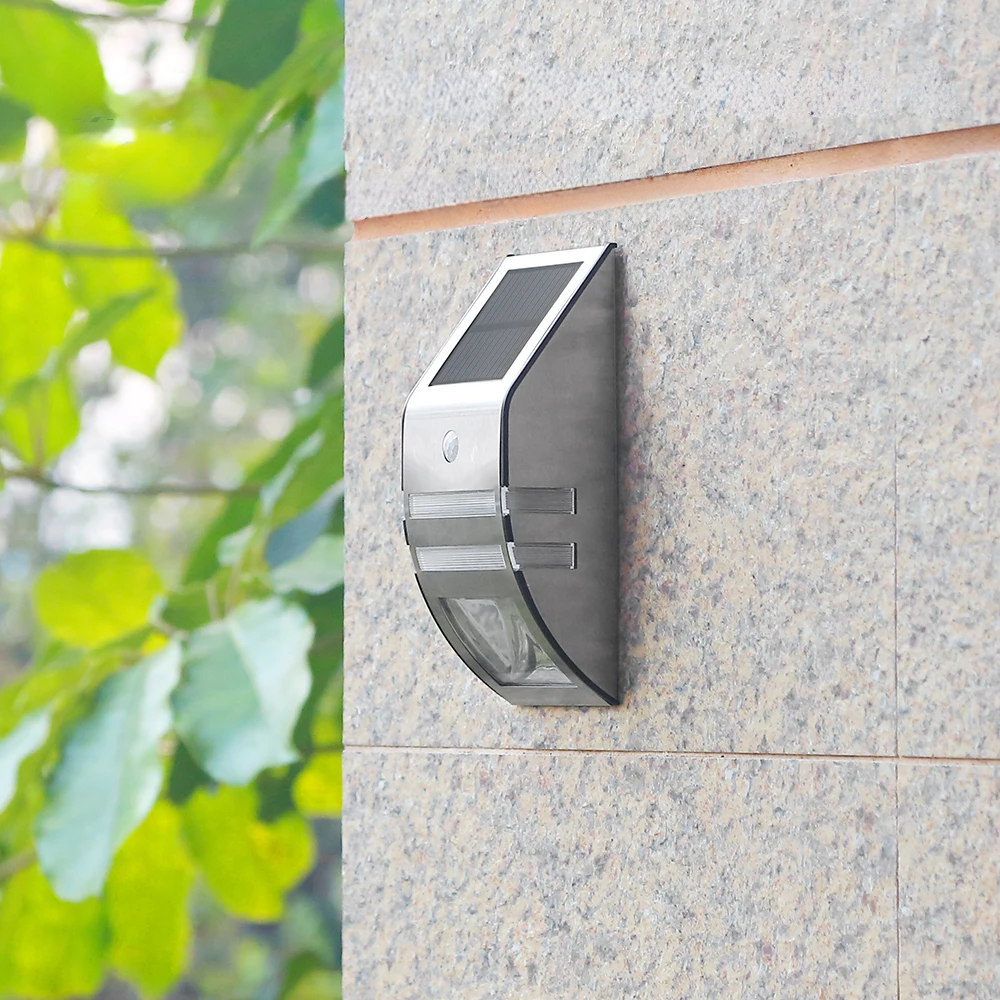 Solar-powered outdoor light fixture on a stone wall with greenery in the background
