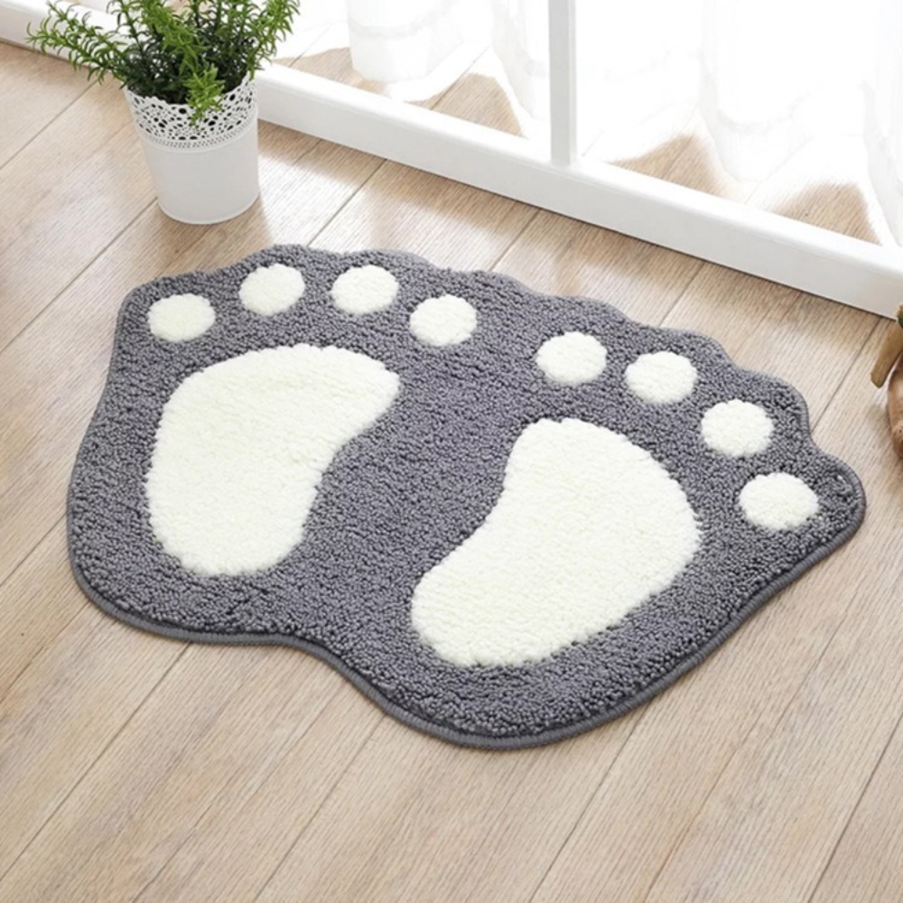 Gray and white paw print rug on a wooden floor with a plant in the background