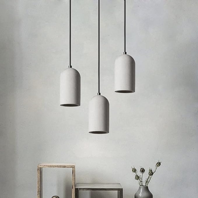 Three white pendant lights hanging against a gray wall with a minimalistic decor.