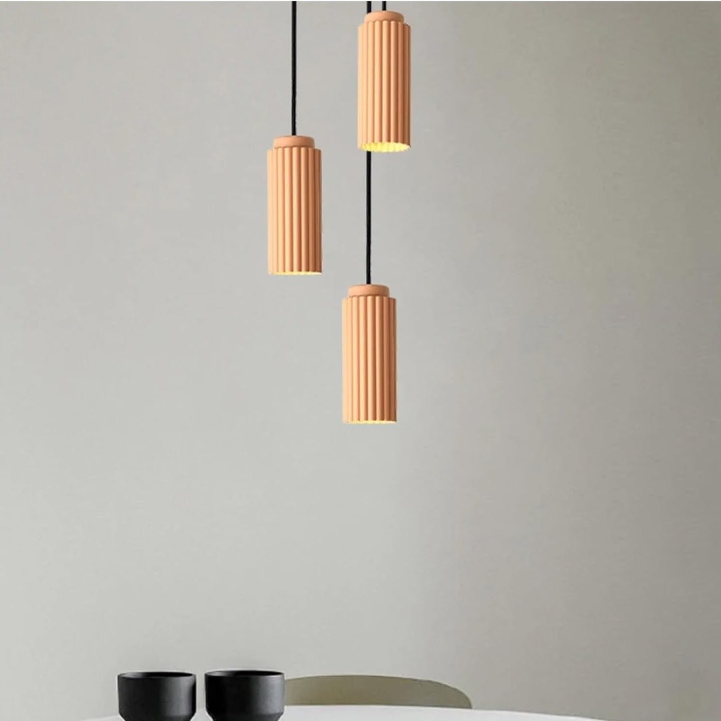 Three cylindrical pendant lights hanging against a plain background