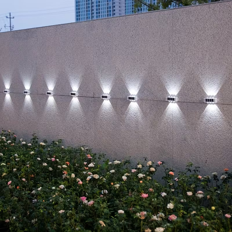 Floral garden with illuminated wall lights against a building backdrop