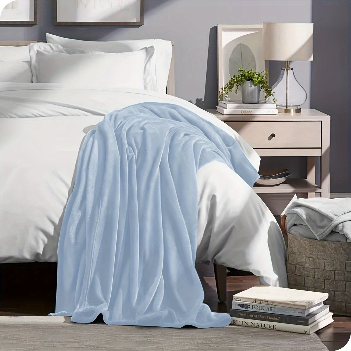 Light blue blanket draped over a bed in a bedroom setting with a nightstand and decor.