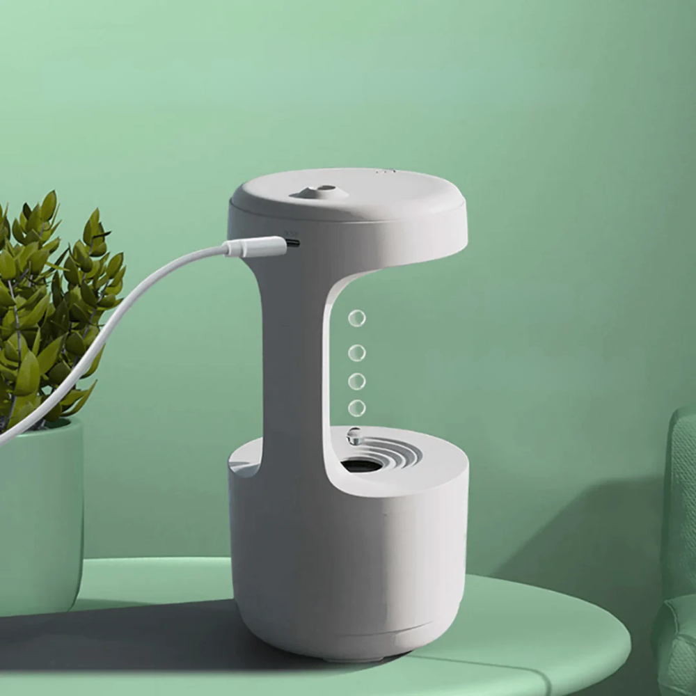 White and gray electronic device on a green surface with a plant in the background