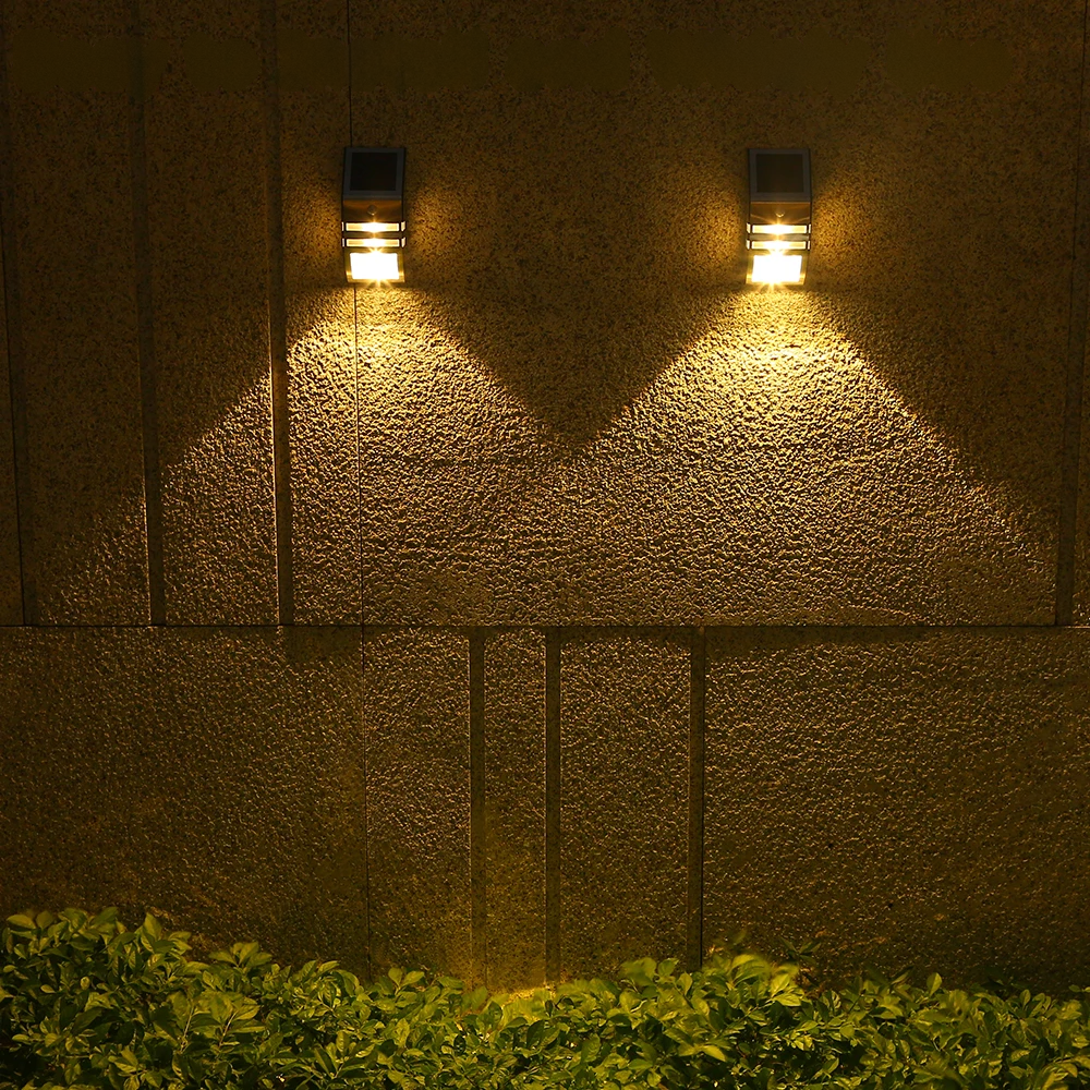 Two outdoor wall lights on a textured wall with grass at the bottom.