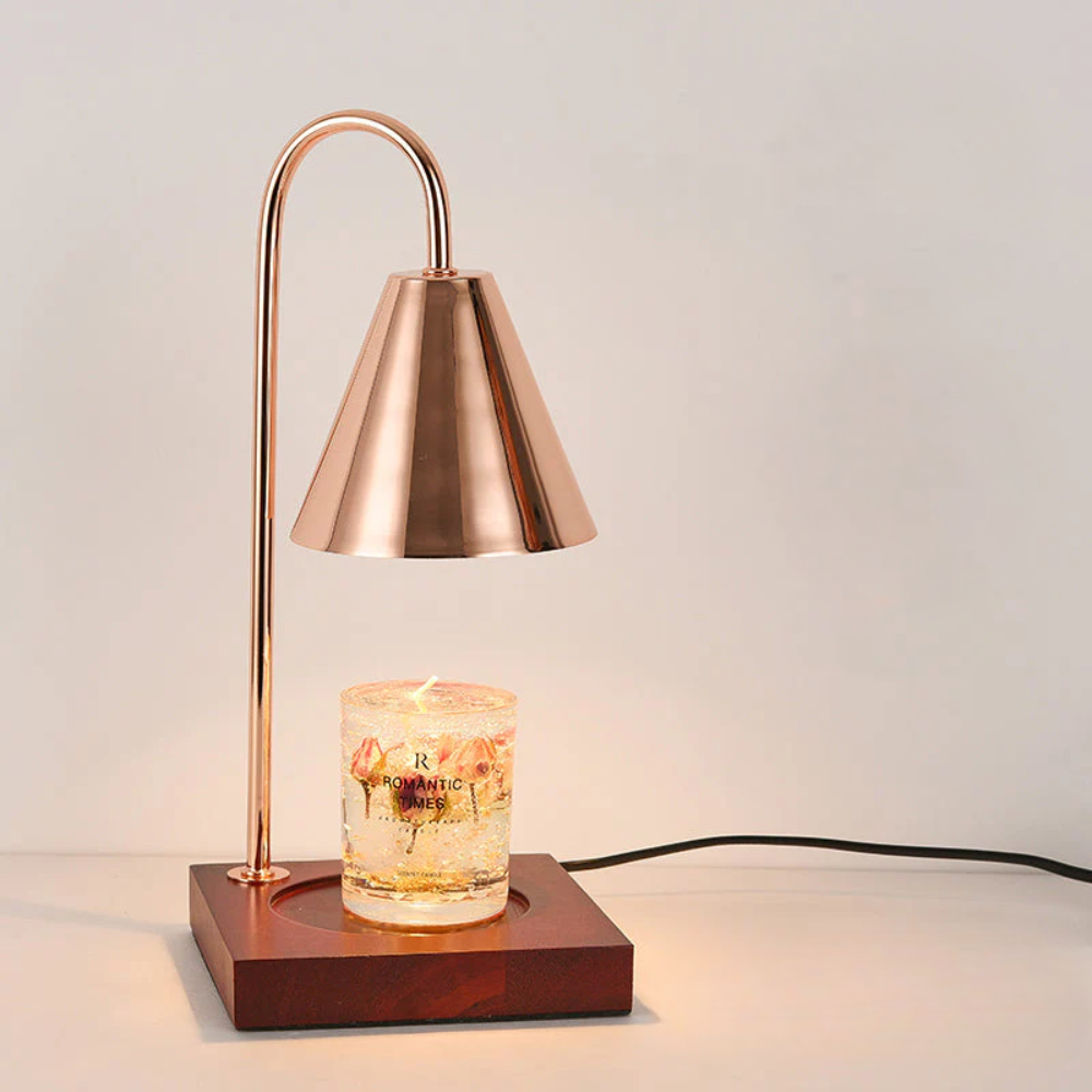 Copper table lamp with a wooden base and a lit candle inside on a neutral background